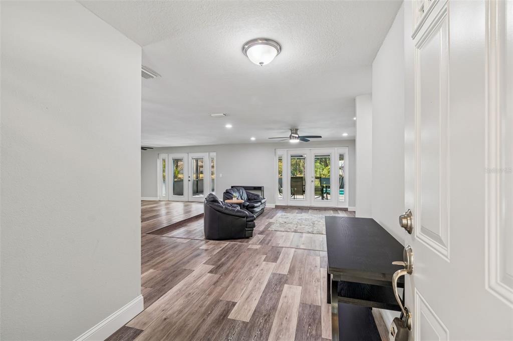An entryway opens into a spacious living room with wood-look flooring and glass patio doors — 10909 CANDY LANE, NEW PORT RICHEY, FL