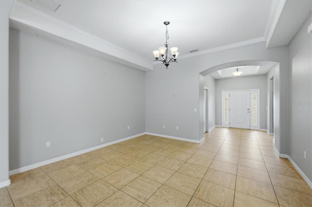 An empty dining room with light gray walls, tile flooring, and a decorative chandelier — 12218 LAVENDER LOOP, BRADENTON, FL
