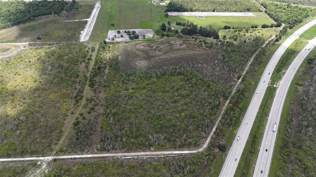 An aerial view shows a large, undeveloped plot of land adjacent to a multi-lane highway — 21061 GRANVILLE ROAD, NORTH FORT MYERS, FL