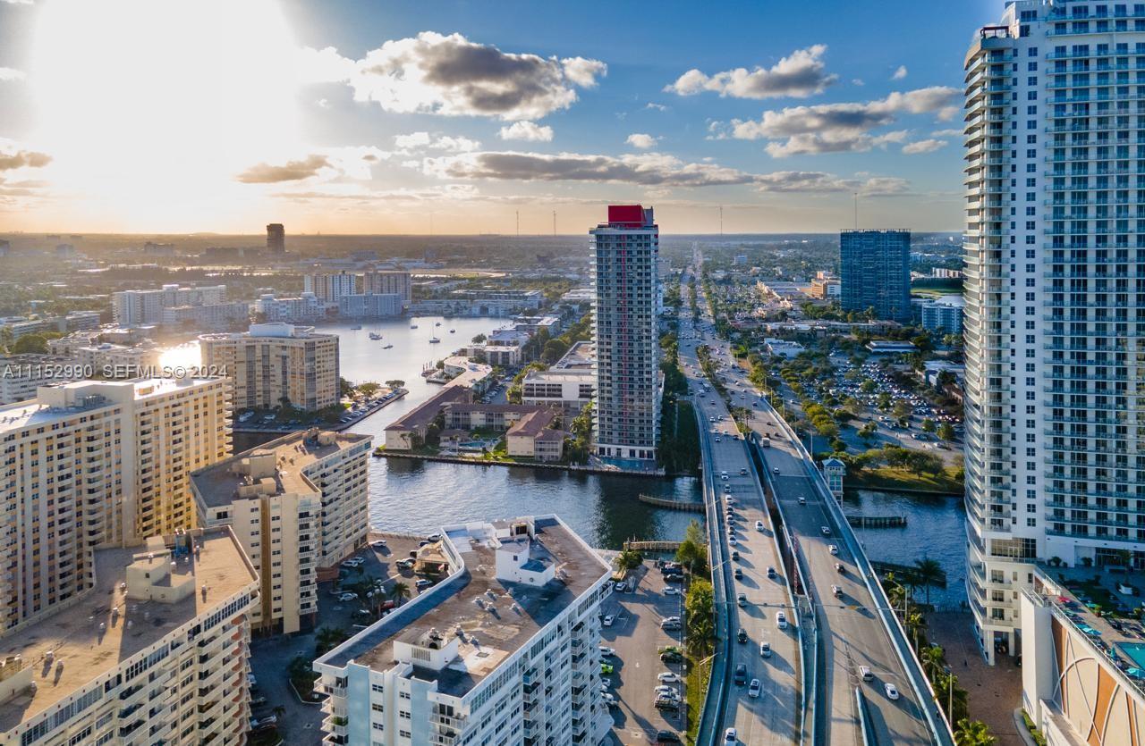 An aerial view shows a city skyline with high-rise buildings, a highway, and a waterway — 1830 OCEAN DR # 4710, Hallandale Beach FL 33009, HALLANDALE BEACH, FL
