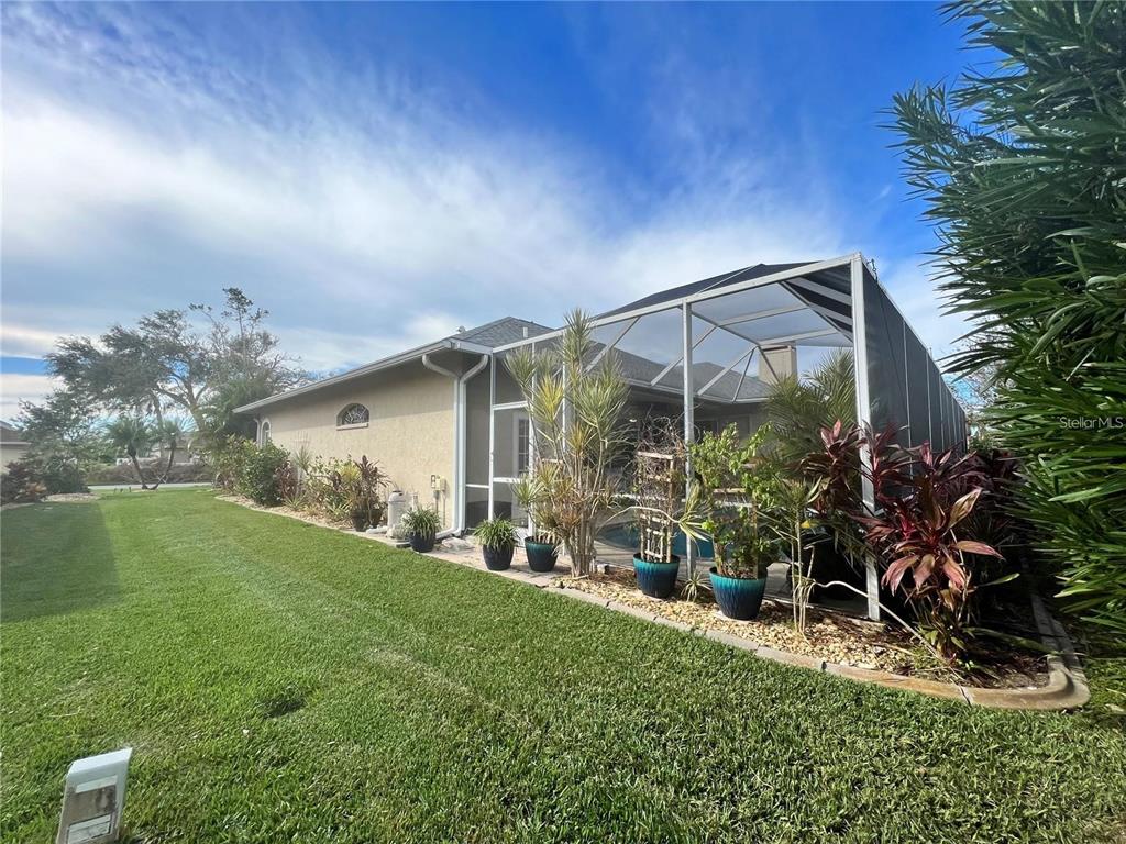 A side view of a house with a screened-in pool enclosure and potted plants — 5831 CLEVELAND ROAD, VENICE, FL