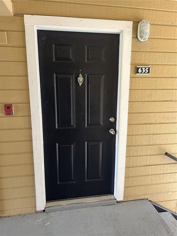 A black front door with a silver knocker and handle is set in a yellow wall — 1083 S HIAWASSEE ROAD UNIT 635, ORLANDO, FL