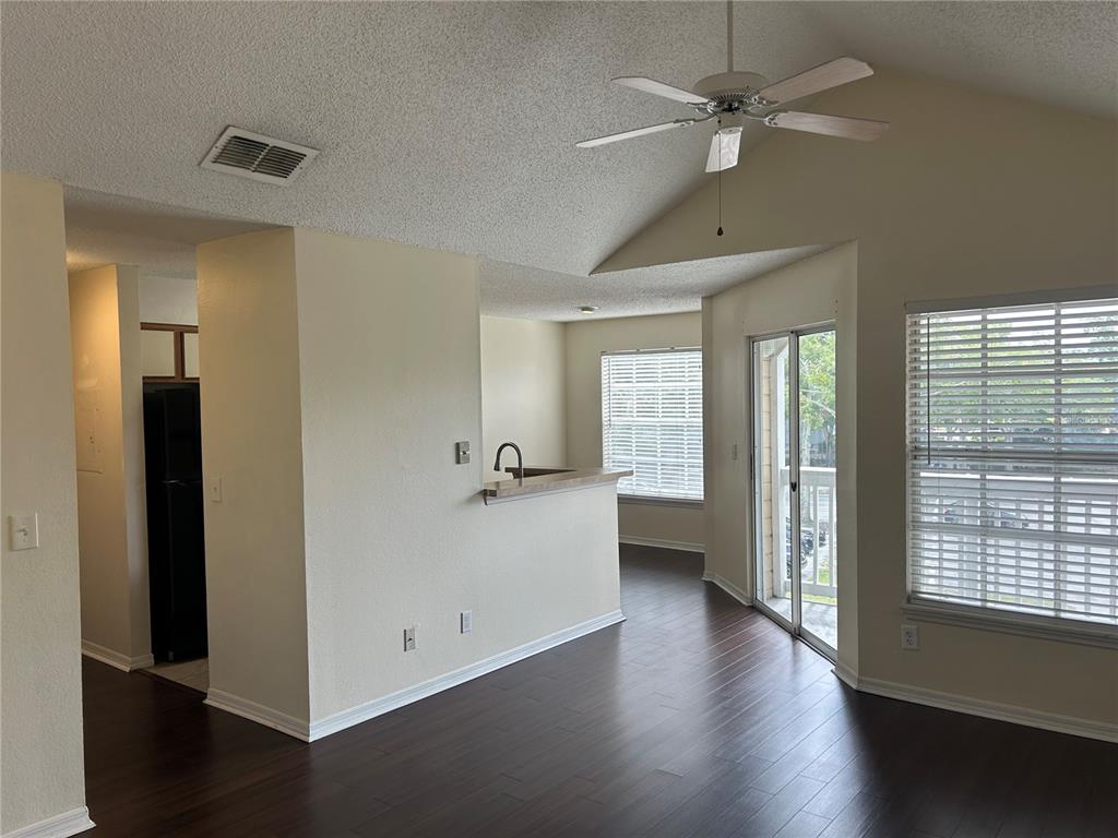 A living room with dark wood flooring, a ceiling fan, and a kitchen pass-through window — 1083 S HIAWASSEE ROAD UNIT 635, ORLANDO, FL