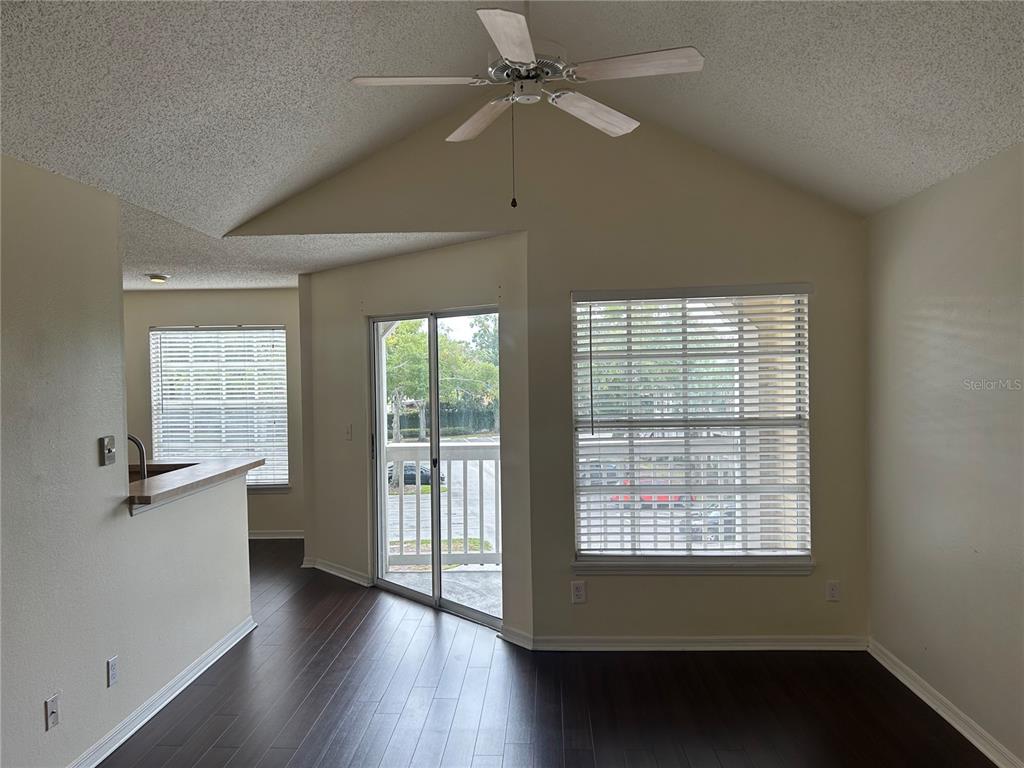 A room with dark wood flooring, a vaulted ceiling, a ceiling fan, and sliding glass doors — 1083 S HIAWASSEE ROAD UNIT 635, ORLANDO, FL