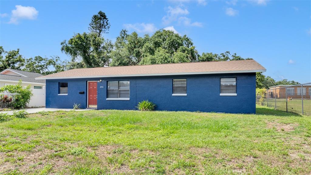 A single-story blue house with a red front door sits on a grassy lot — 2551 26TH AVENUE S, ST PETERSBURG, FL