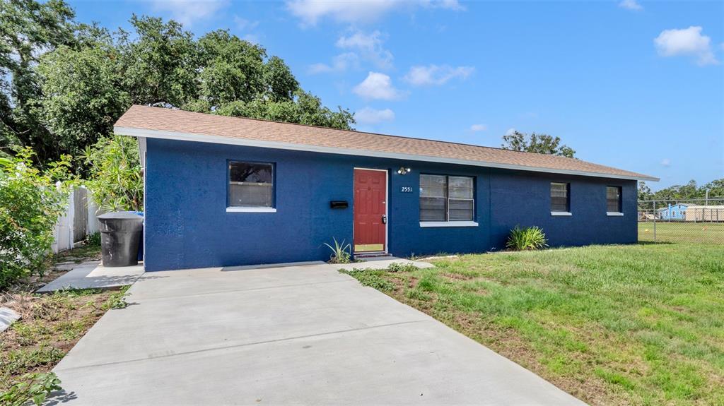 A blue single-story house with a red front door and a concrete driveway — 2551 26TH AVENUE S, ST PETERSBURG, FL