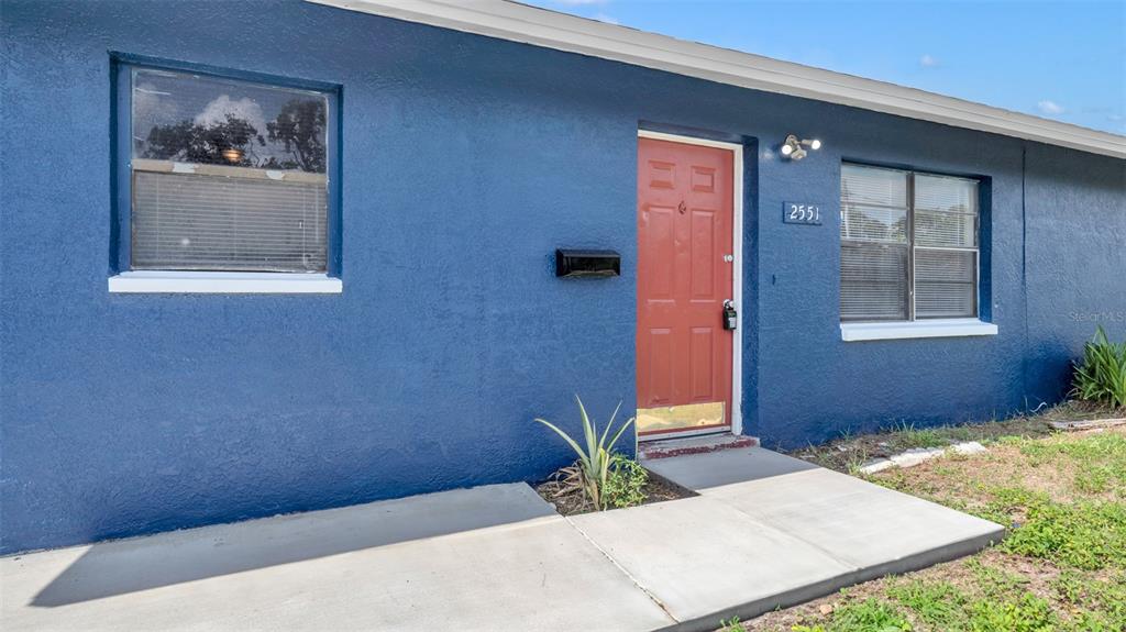 The exterior of a blue house features a red front door and a concrete walkway — 2551 26TH AVENUE S, ST PETERSBURG, FL