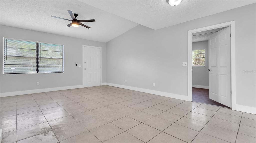An empty room with light gray walls, beige tile flooring, a ceiling fan, and two doors — 2551 26TH AVENUE S, ST PETERSBURG, FL