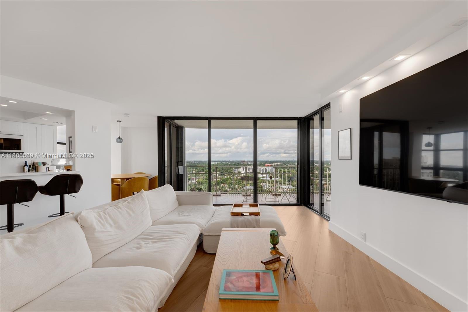 A modern living room features a white sectional sofa, light wood floors, and floor-to-ceiling windows — 4000 Towerside Ter # 2211, Miami FL 33138, MIAMI, FL