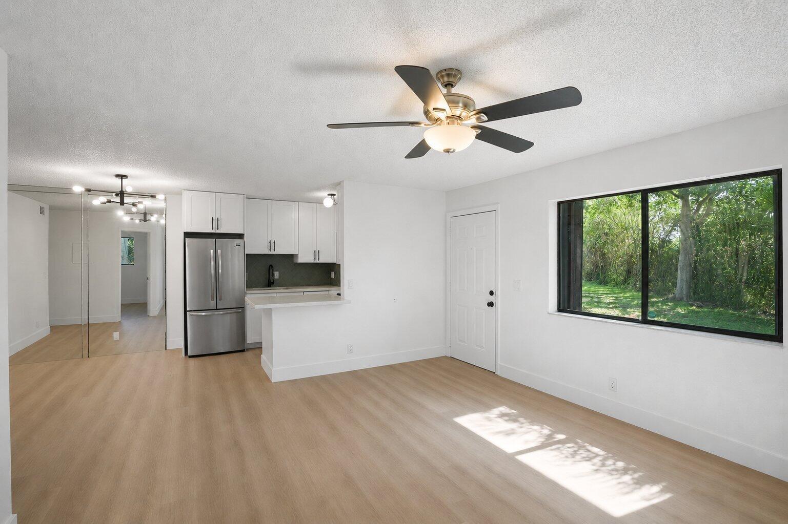 A bright room with light wood flooring, a ceiling fan, a kitchen, and a window — 588 Trace Circle # 102, Deerfield Beach FL 33441, DEERFIELD BEACH, FL