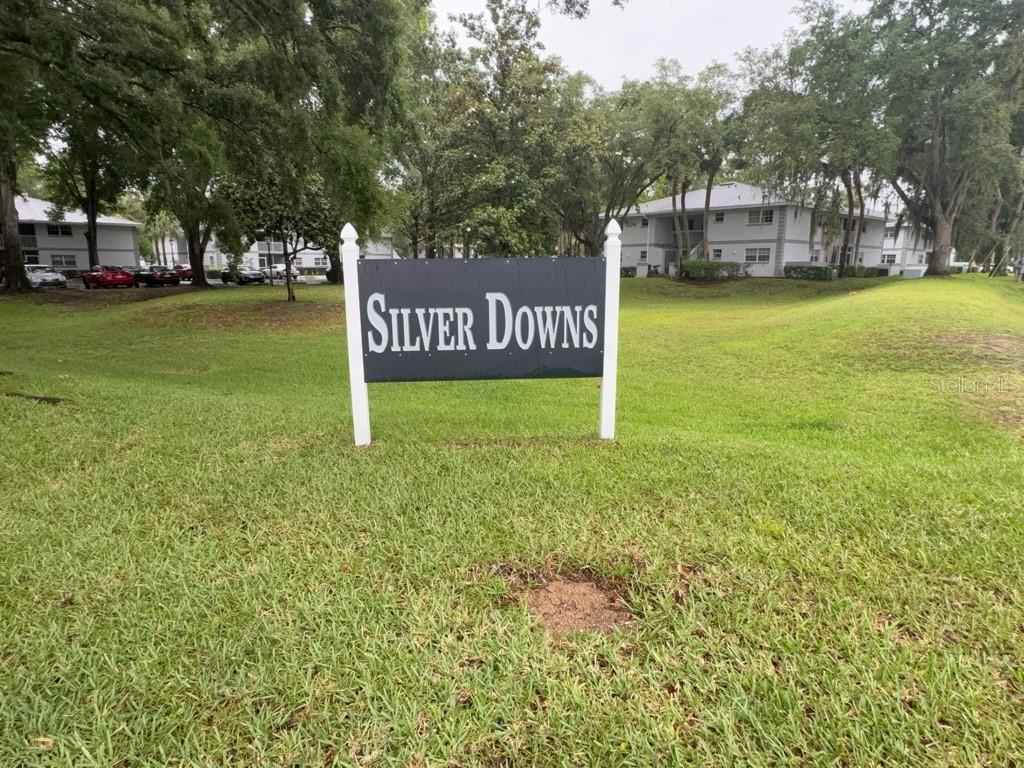 A sign for Silver Downs stands in a grassy lawn in front of apartment buildings — 454 FAIRWAYS CIRCLE UNIT B204, OCALA, FL