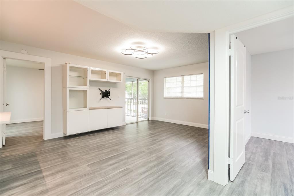 A living room features light gray wood-look flooring, a white built-in cabinet, and a sliding door — 454 FAIRWAYS CIRCLE UNIT B204, OCALA, FL