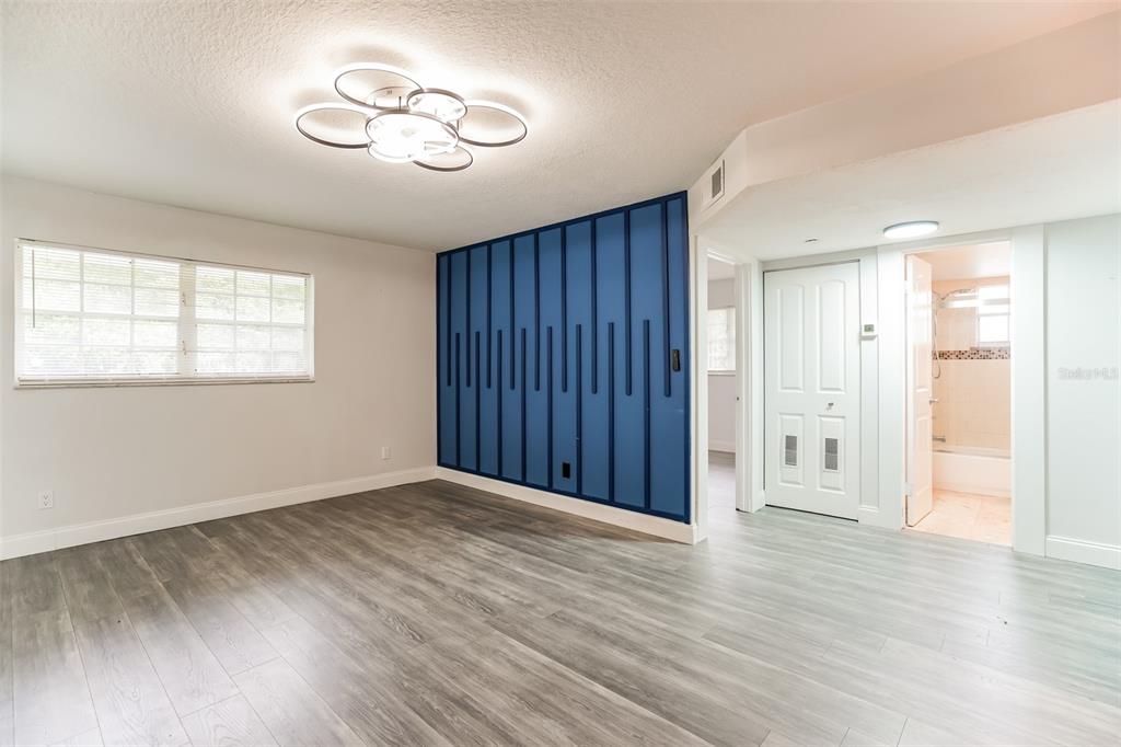A room with gray wood-look flooring, a blue accent wall, and a modern ceiling light — 454 FAIRWAYS CIRCLE UNIT B204, OCALA, FL