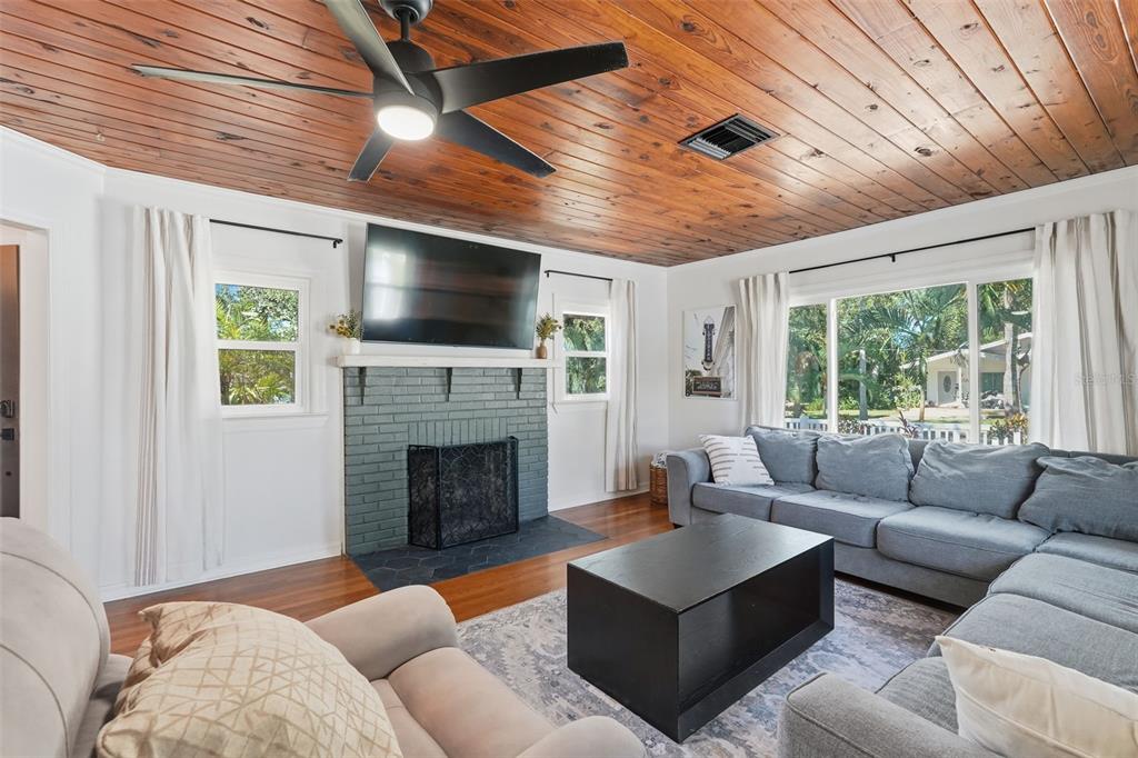 A living room features a wood-paneled ceiling, a gray brick fireplace, and a sectional sofa — 517 AVERY AVENUE, CRYSTAL BEACH, FL