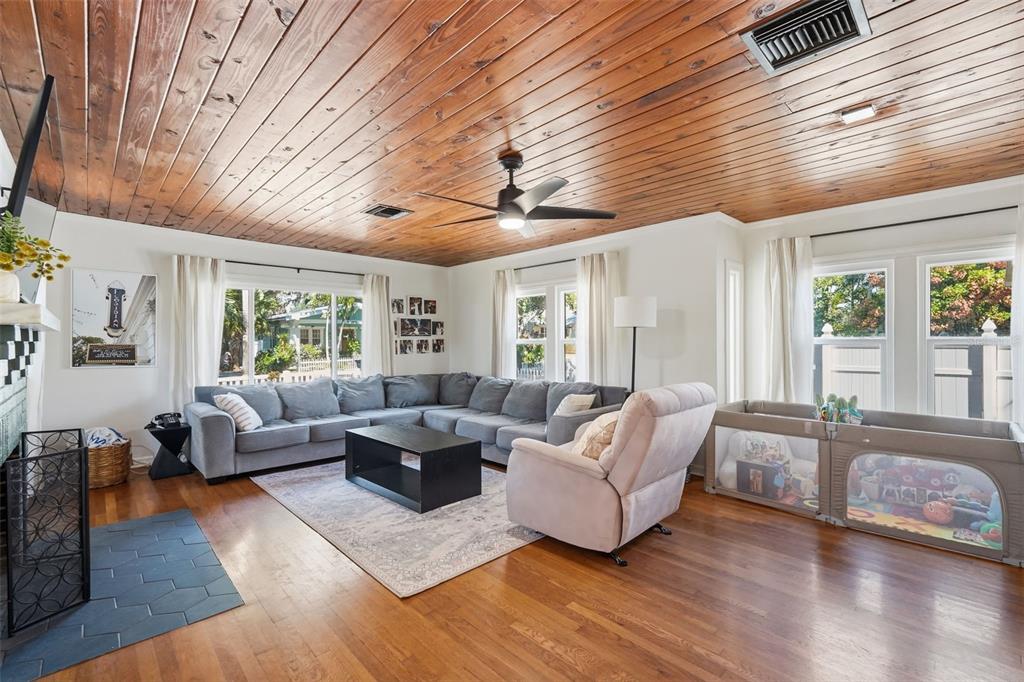 A living room features a wood-plank ceiling, hardwood floors, a sectional sofa, and a playpen — 517 AVERY AVENUE, CRYSTAL BEACH, FL