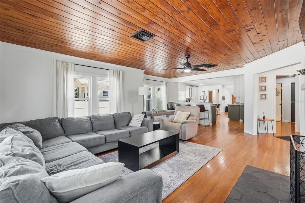 A living room with a wood-paneled ceiling, gray sectional sofa, and hardwood floors — 517 AVERY AVENUE, CRYSTAL BEACH, FL