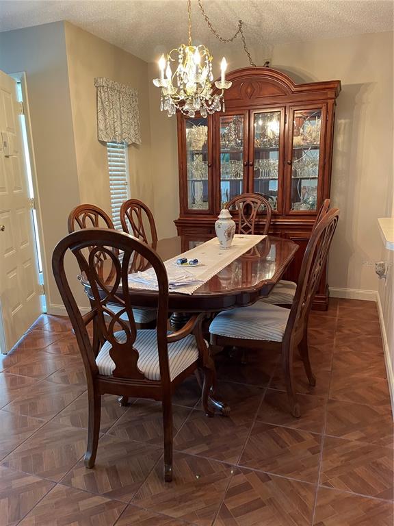 A dining room features a wooden table, six chairs, a hutch, and a crystal chandelier — 2688 PINE RIDGE WAY N UNIT D2, PALM HARBOR, FL