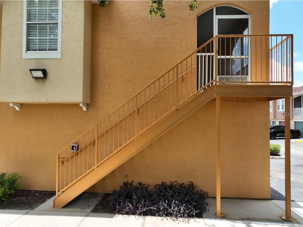 An exterior view shows a metal staircase leading to a second-story landing and doorway — 12208 WILD IRIS WAY UNIT 110, ORLANDO, FL