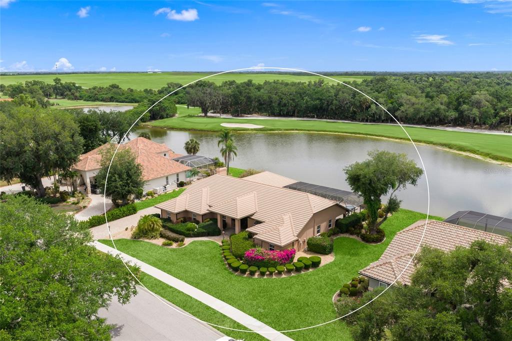 An aerial view of a single-story house with a tile roof situated by a lake — 8838 WILD DUNES DRIVE, SARASOTA, FL