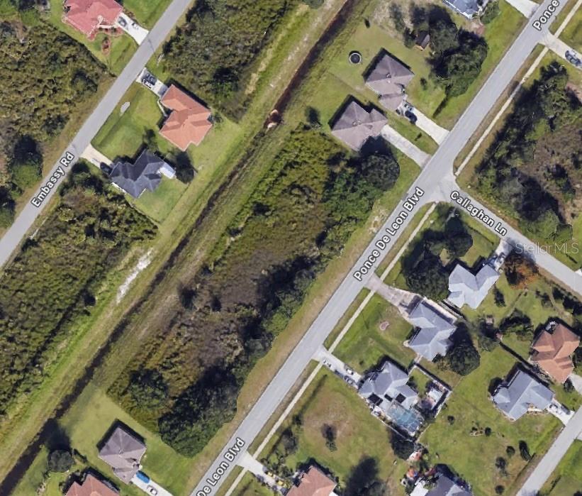 This is an aerial map view showing residential houses, streets, and a vegetated drainage canal — 15 PONCE DE LEON BOULEVARD, NORTH PORT, FL