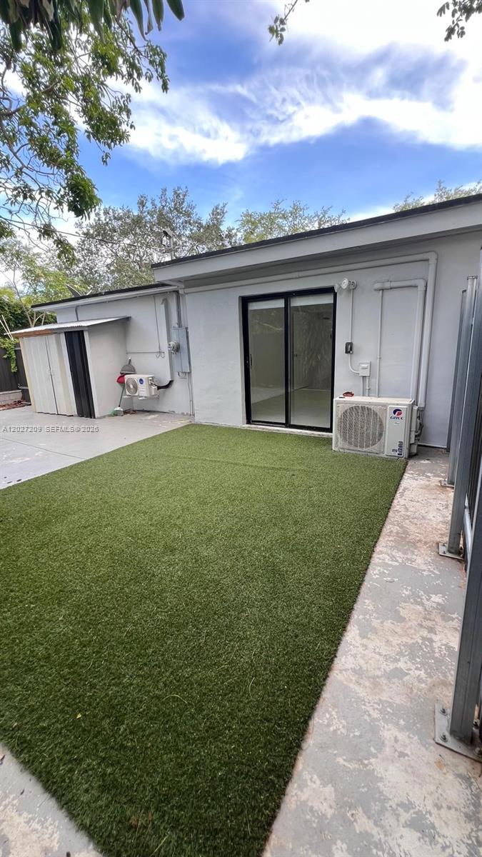 A backyard features a patch of artificial turf, a sliding glass door, and two air-conditioning units — 841 S 24th Ave # B, Hollywood FL 33020, HOLLYWOOD, FL