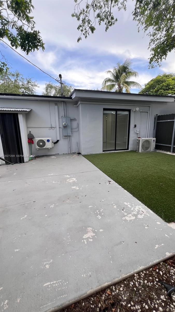 A gray exterior wall features a sliding glass door, two air conditioning units, and concrete — 841 S 24th Ave # B, Hollywood FL 33020, HOLLYWOOD, FL