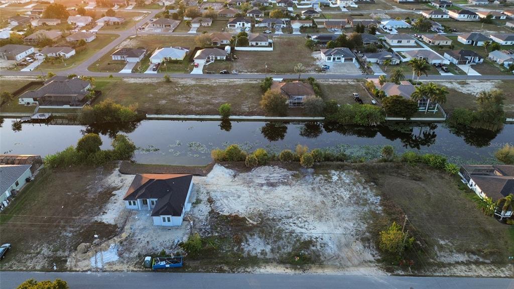 An aerial view shows a newly constructed house on a large, vacant waterfront lot — 1314 NE 6TH AVENUE, CAPE CORAL, FL