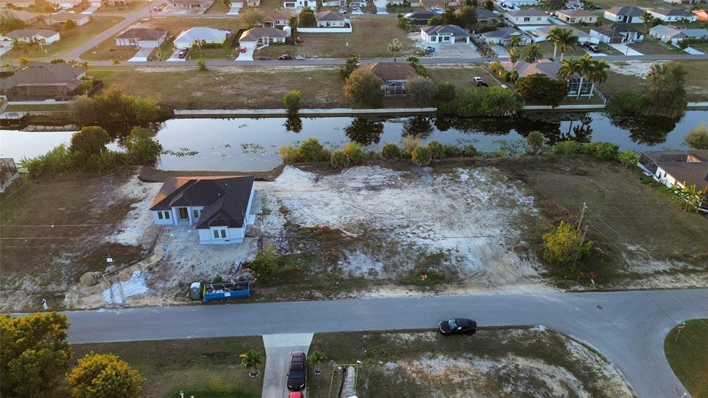 An aerial view shows a newly constructed house on a large, sandy waterfront lot — 1314 NE 6TH AVENUE, CAPE CORAL, FL