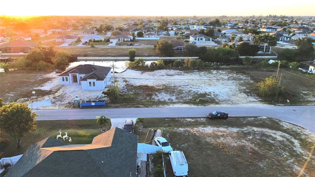 An aerial view shows a residential lot with a house under construction near a canal — 1314 NE 6TH AVENUE, CAPE CORAL, FL