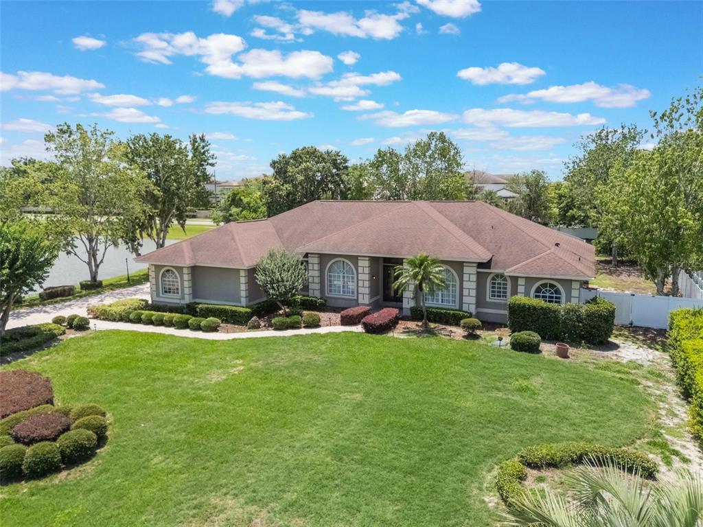 A single-story house with a brown roof and gray exterior sits behind a large lawn — 12718 WINDERMERE ISLES PLACE, WINDERMERE, FL