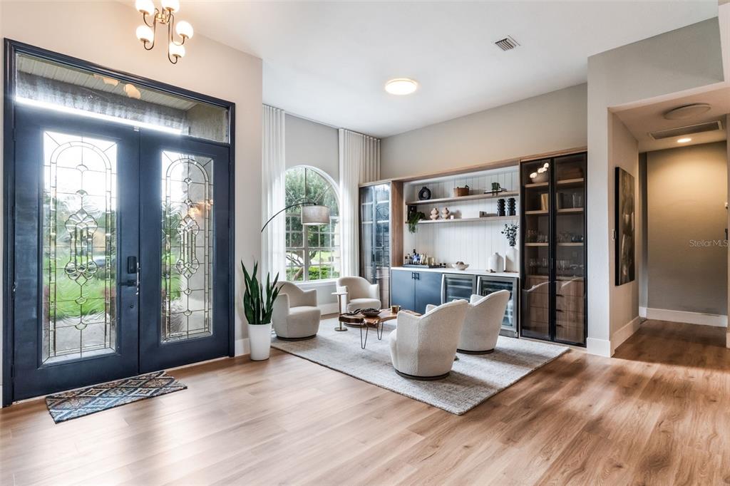 A bright foyer features light wood floors, a dark double door, and a built-in bar — 12718 WINDERMERE ISLES PLACE, WINDERMERE, FL