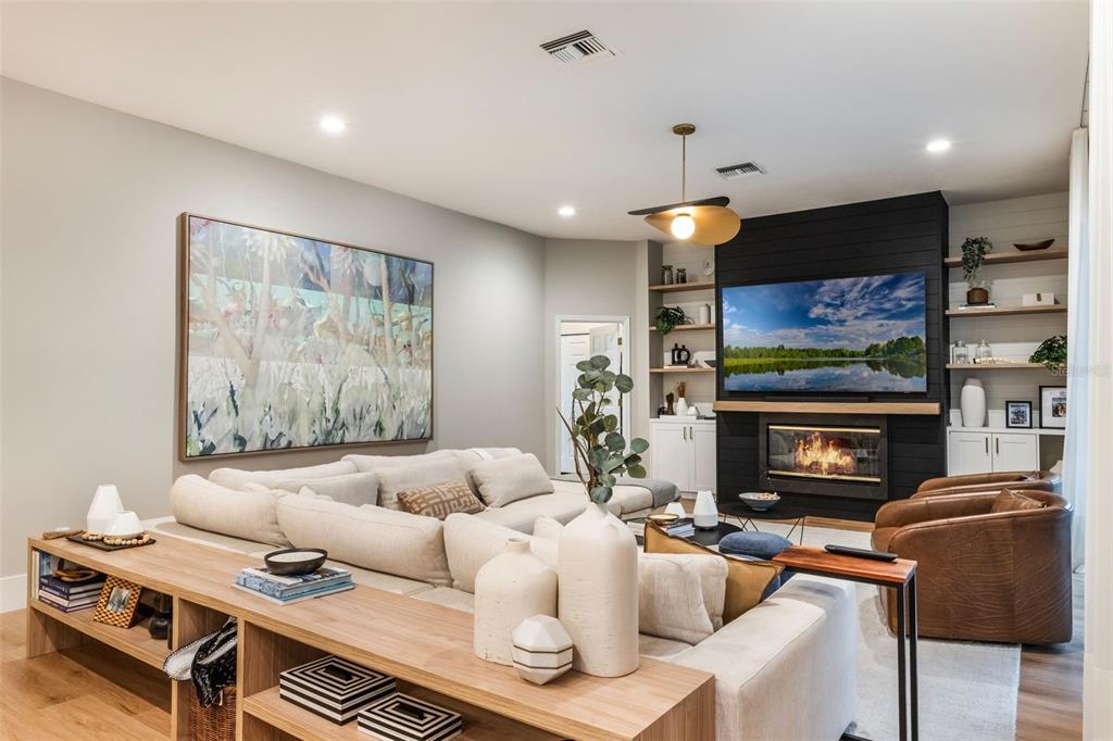 A living room features a large sectional sofa, a fireplace with a black shiplap wall, and shelving — 12718 WINDERMERE ISLES PLACE, WINDERMERE, FL