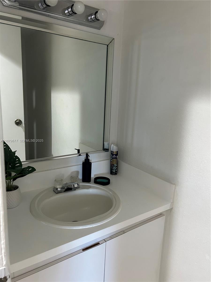 A bathroom features a white vanity with a sink, a mirror, and overhead lighting — 17901 NW 68th Ave # R209, Hialeah FL 33015, HIALEAH, FL
