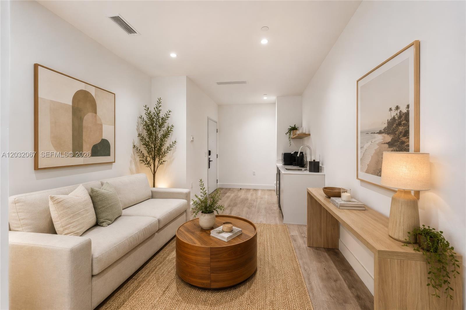 A living room features a beige sofa, a round wooden coffee table, and a kitchenette — 239 SW 9TH St # 301, Miami FL 33130, MIAMI, FL