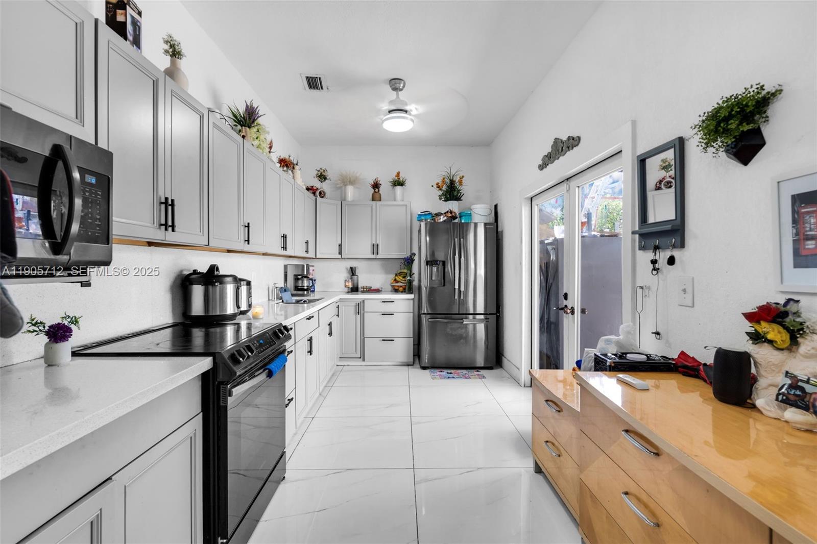 A kitchen features light gray cabinets, stainless steel appliances, white countertops, and white tile flooring — 3166 NW 102nd St, Miami FL 33147, MIAMI, FL