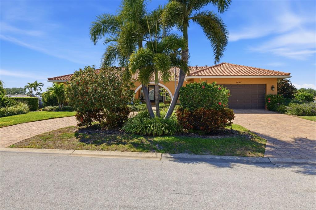 A single-story house with a tile roof, paved driveway, and palm trees in the front yard — 1997 HAWAII AVENUE NE, ST PETERSBURG, FL