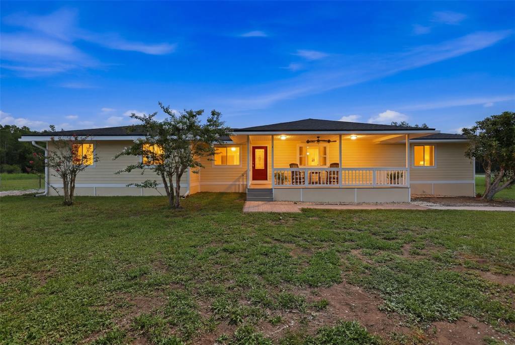 A single-story yellow house with a covered front porch and a red front door — 4700 TOWER ROAD, LAND O LAKES, FL