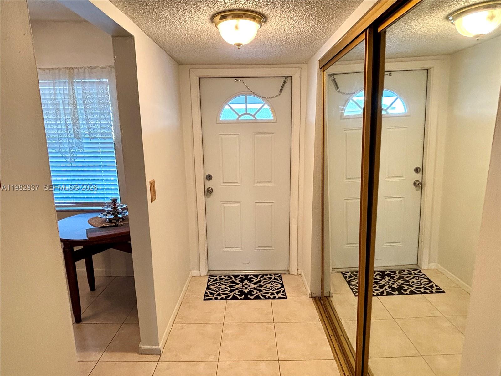 An entryway features a white front door, tiled floors, and a mirrored sliding closet door — 601 NW 80th Ave # 207, Margate FL 33063, MARGATE, FL
