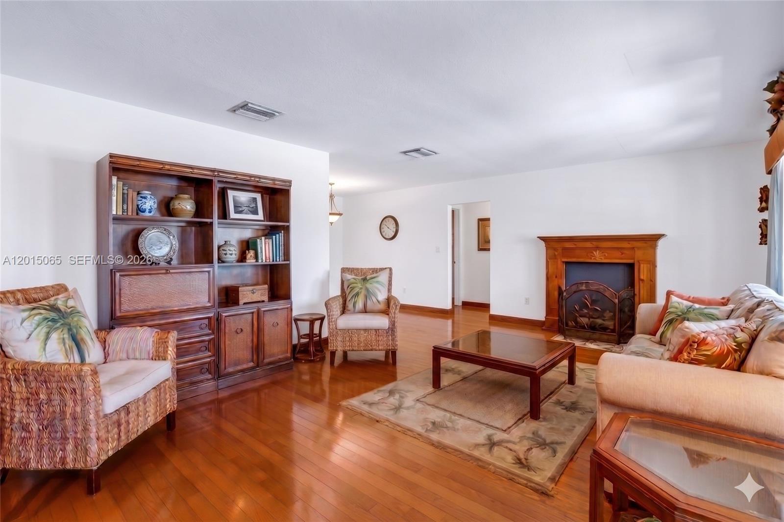 A living room features hardwood floors, a wooden fireplace, and wicker armchairs — 4605 NW 47th Ct, Tamarac FL 33319, TAMARAC, FL
