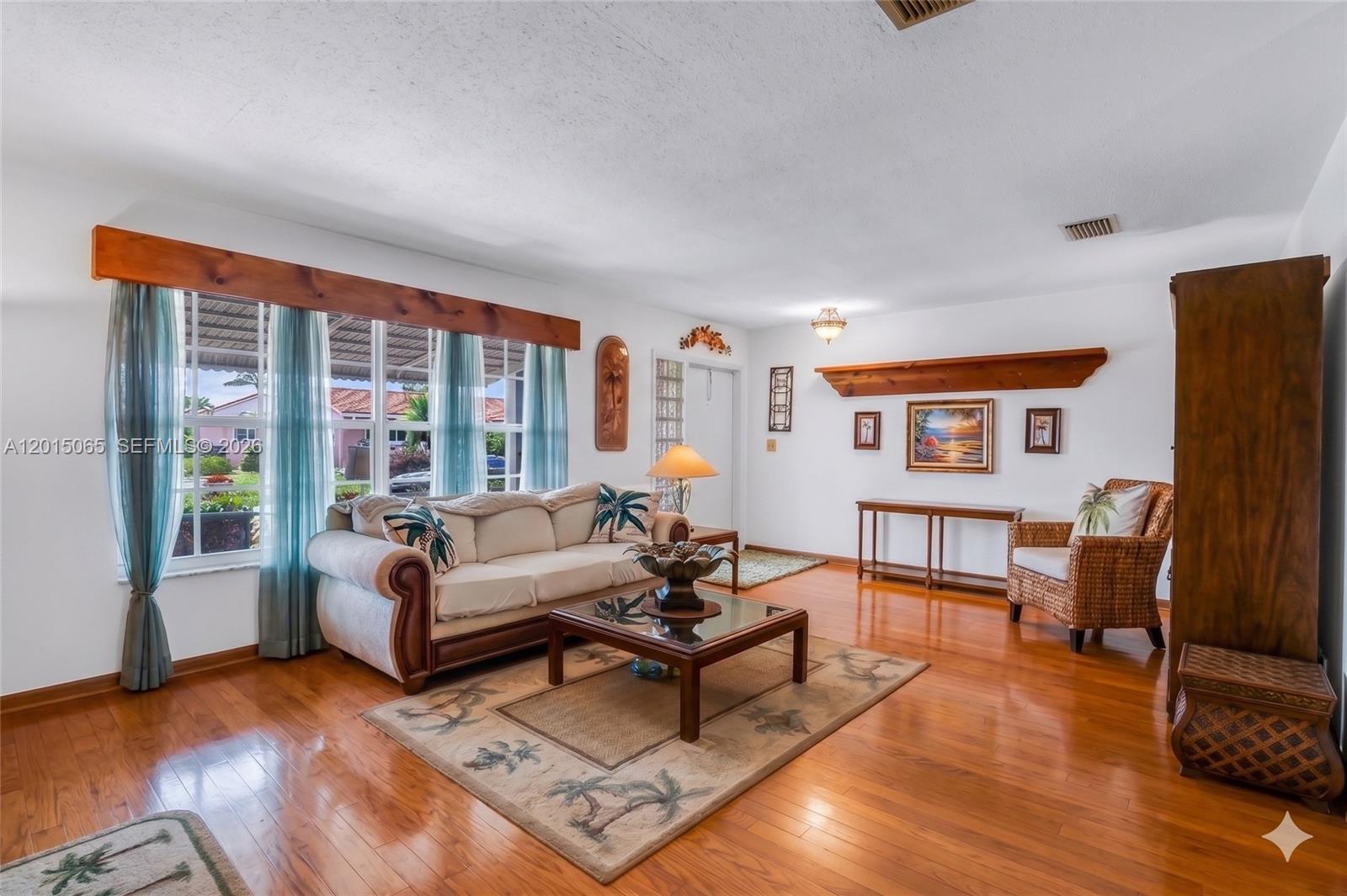 A living room features hardwood floors, a sofa, a wicker chair, and a wooden mantel — 4605 NW 47th Ct, Tamarac FL 33319, TAMARAC, FL