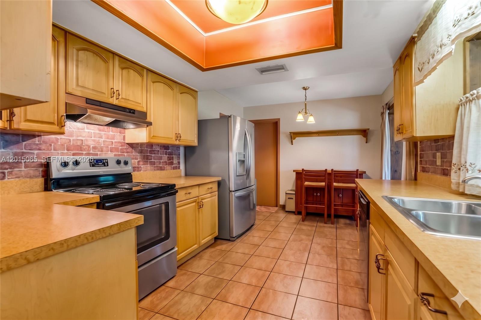 A kitchen features light wood cabinets, stainless steel appliances, a brick backsplash, and tile flooring — 4605 NW 47th Ct, Tamarac FL 33319, TAMARAC, FL