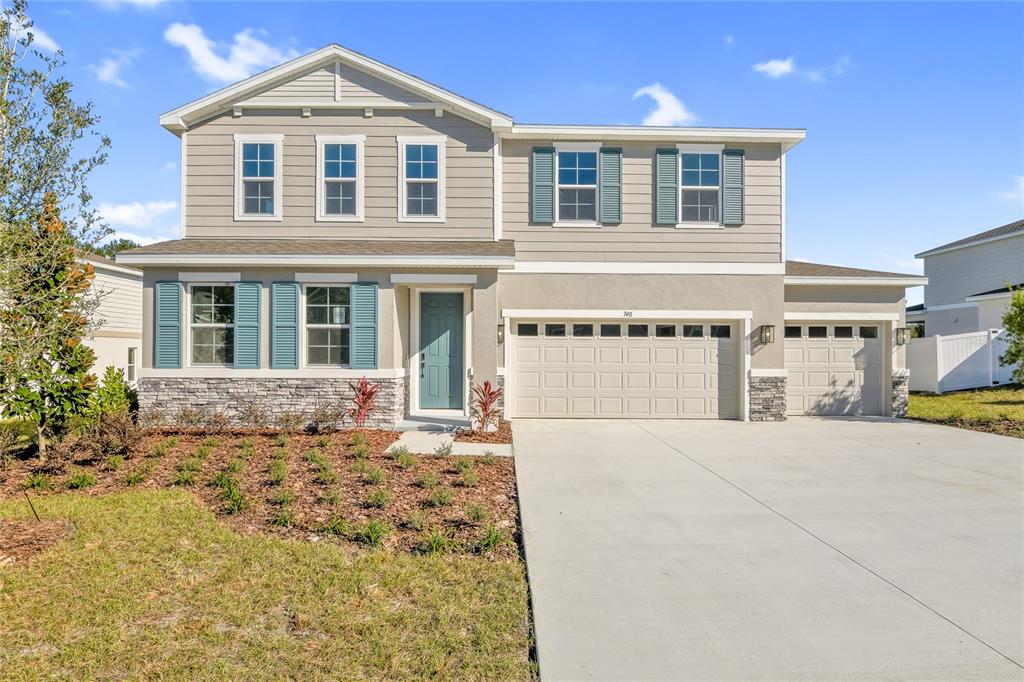 A two-story suburban house with beige siding, stone accents, blue shutters, and a three-car garage — 740 WEKIVA RIDGE DRIVE, MOUNT DORA, FL