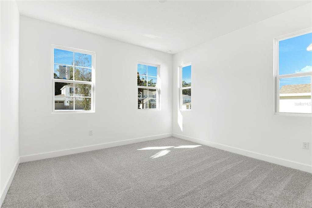 An empty bedroom features white walls, gray carpeting, and four windows — 740 WEKIVA RIDGE DRIVE, MOUNT DORA, FL