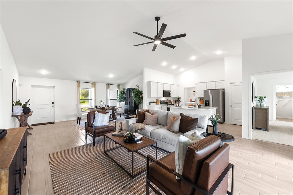 An open-concept living room and kitchen featuring a vaulted ceiling, tile floors, and leather furniture — 10574 N ADLER DRIVE, CITRUS SPRINGS, FL