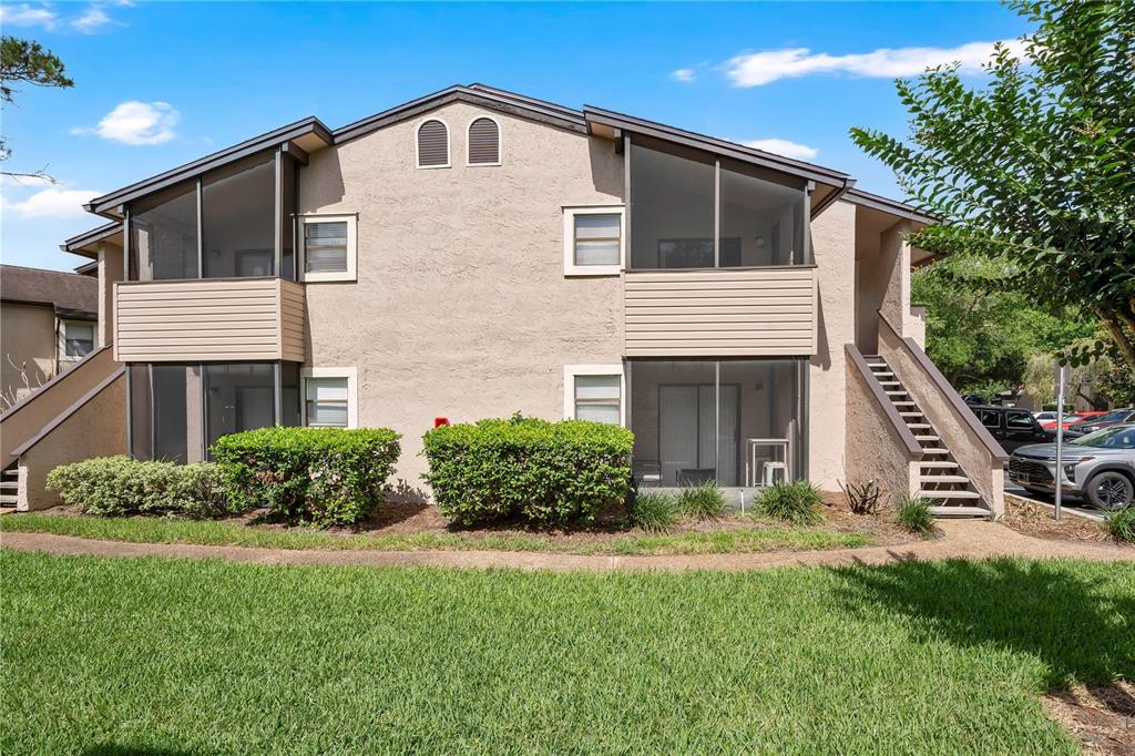 A two-story apartment building with tan stucco walls, screened-in balconies, and an exterior staircase — 2923 ANTIQUE OAKS CIRCLE UNIT 34, WINTER PARK, FL