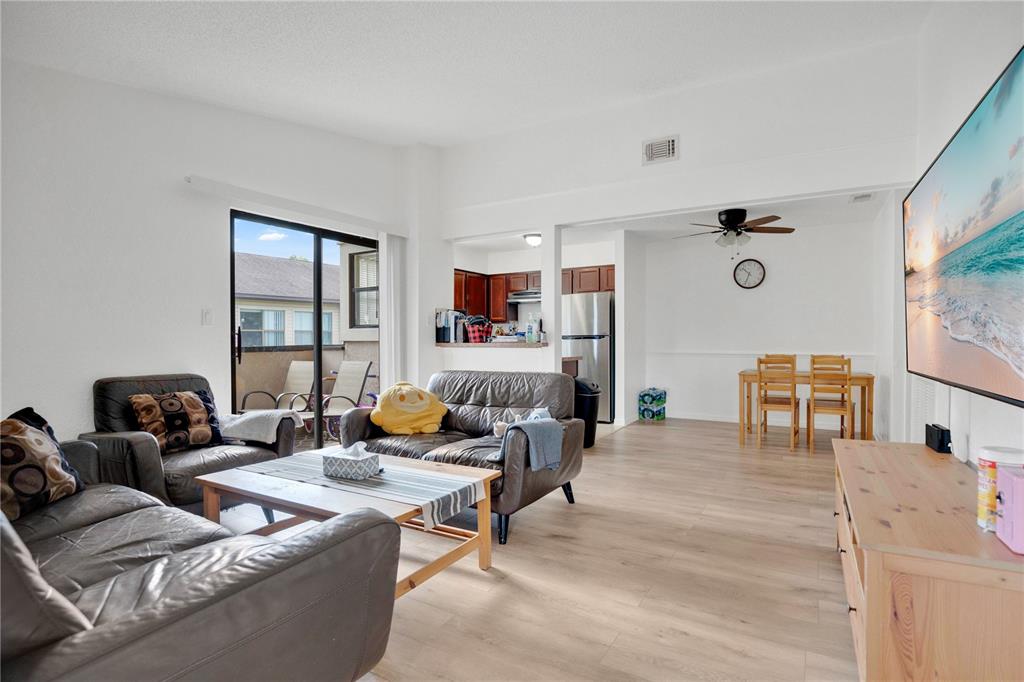 A living room with light wood flooring, leather furniture, and an open view to the kitchen — 2923 ANTIQUE OAKS CIRCLE UNIT 34, WINTER PARK, FL