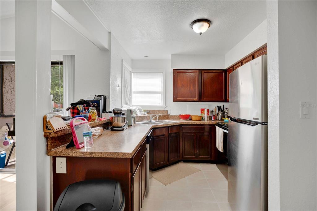 A kitchen features dark wood cabinets, a stainless steel refrigerator, and a laminate countertop — 2923 ANTIQUE OAKS CIRCLE UNIT 34, WINTER PARK, FL