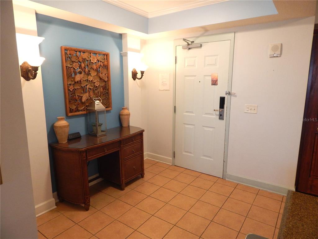 An entryway features a wooden desk, wall sconces, a decorative wall carving, and tiled flooring — 200 OCEAN CREST DRIVE UNIT 717, PALM COAST, FL