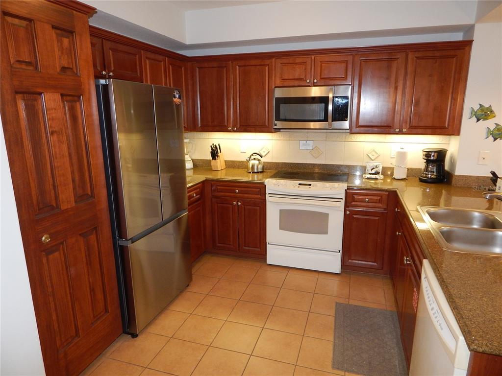A kitchen featuring wood cabinets, stainless steel appliances, a white stove, and granite countertops — 200 OCEAN CREST DRIVE UNIT 717, PALM COAST, FL