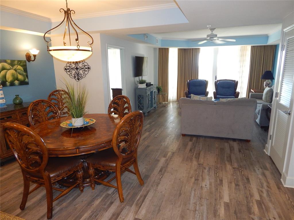 An open-concept living and dining area features wood-look flooring, a round wooden table, and furniture — 200 OCEAN CREST DRIVE UNIT 717, PALM COAST, FL